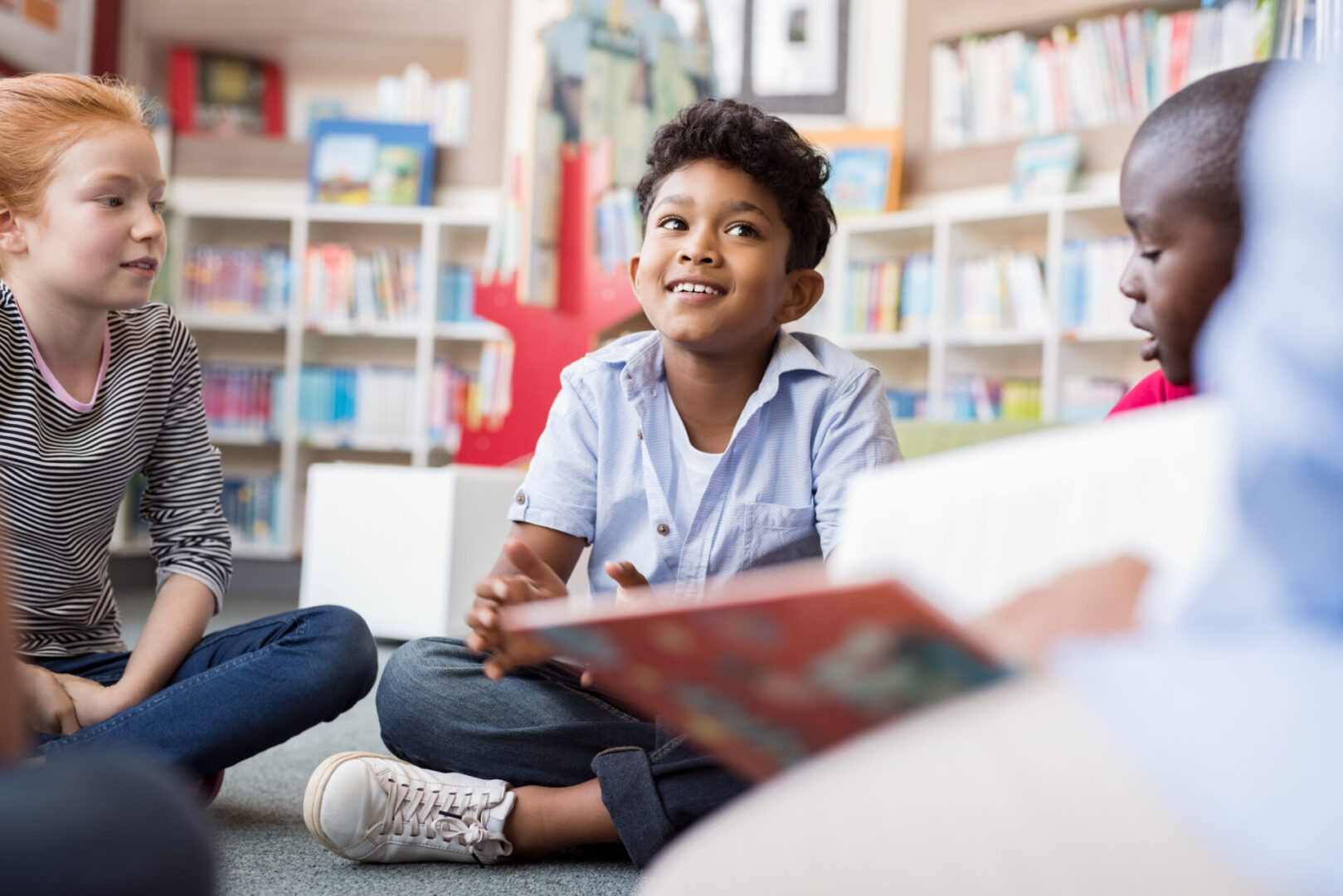 A boy sitting on the floor in front of books
